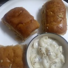A picture of Pasta in white sauce with garlic bread.