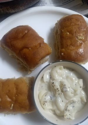 A picture of Pasta in white sauce with garlic bread.