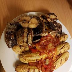 A picture of Grilled fish and plantain with tomato sauce.