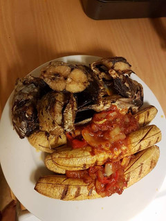 A picture of Grilled fish and plantain with tomato sauce.