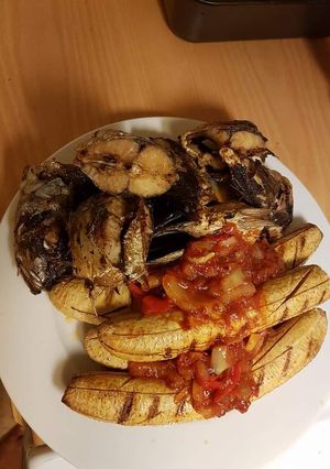 A picture of Grilled fish and plantain with tomato sauce.