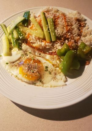 A picture of Rice with green veggies and a fried egg.