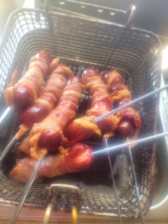 A picture of Deep-Fried, Bacon-Wrapped Hot Dogs on Skewers.
