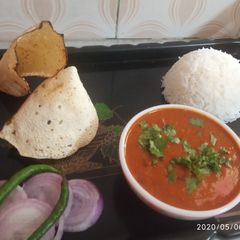 A picture of Rajma rice with papad and onion salad.