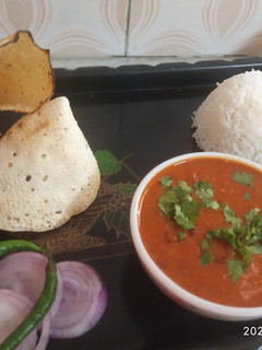 A picture of Rajma rice with papad and onion salad.