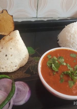 A picture of Rajma rice with papad and onion salad.