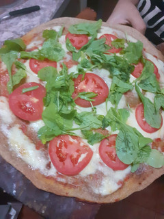 Una foto de Pizza Integral de rúcula y tomate!