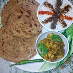 A picture of Lachha paratha with masala Arbi and raiyta.