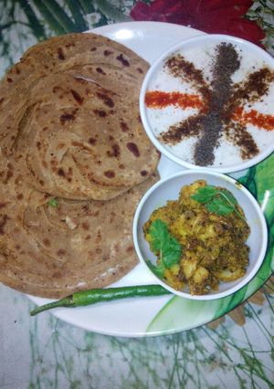 A picture of Lachha paratha with masala Arbi and raiyta.