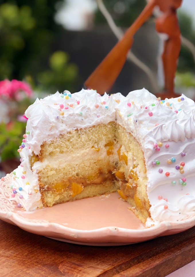 Una foto de Bizcochuelo relleno, con dulce de leche, crema y duraznos