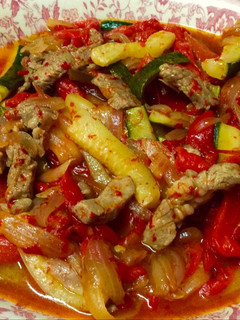 Una foto de Cordero con pimientos rojos, calabacín y cebolla