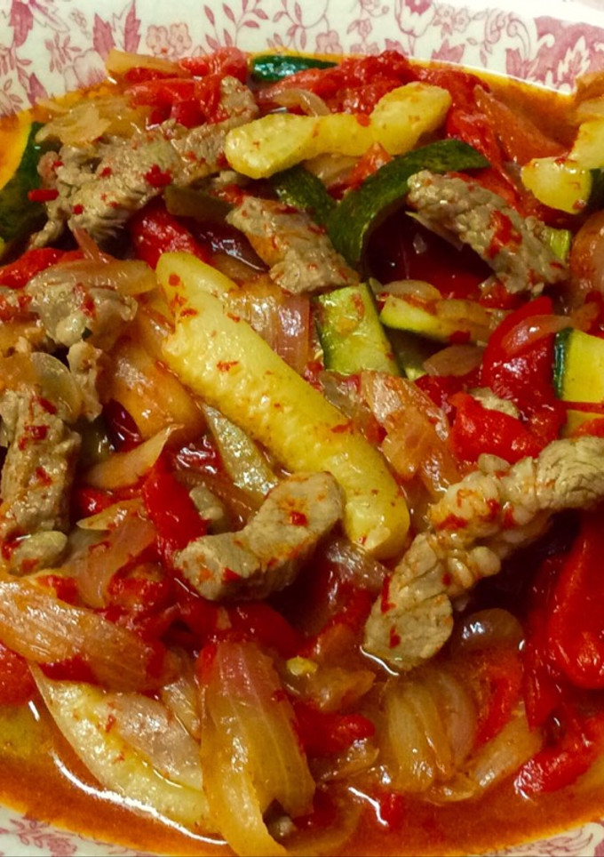 Una foto de Cordero con pimientos rojos, calabacín y cebolla