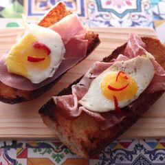 A picture of Bruschette with ham and quail eggs.