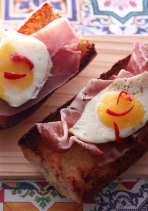 A picture of Bruschette with ham and quail eggs.