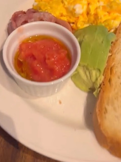Una foto de Tosta de aguacate, tomate, huevo revuelto y jamón serrano