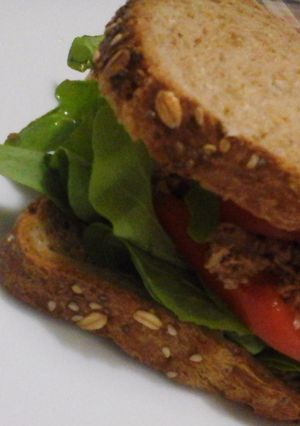 Una foto de Sándwich de pan integral multicereal bajo en sal con atún, tomate y rúcula