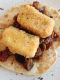 Caponata siciliana con bacalao empanado sobre pan naan