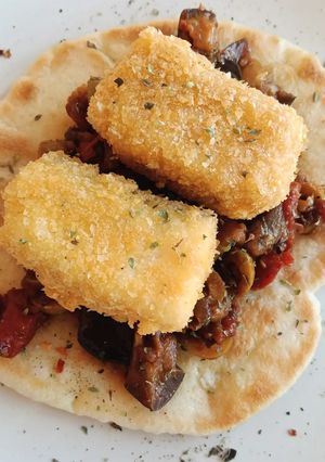 Foto principal de Caponata siciliana con bacalao empanado sobre pan Naan