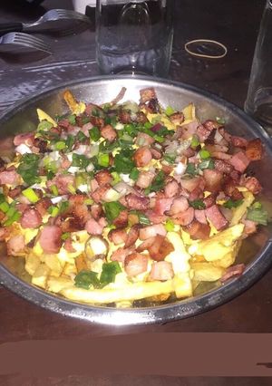 Una foto de Papas con cheddar, bacon y verdeo