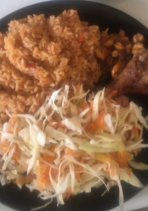 A picture of Jollof Rice with salad,pan fried shrimps with fried chicken.