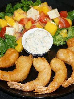 Una foto de Camarones fritos con batido de cerveza y ensalada de mango con queso de cabra