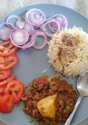 A picture of Karahi qeema matar with brown onion rice.