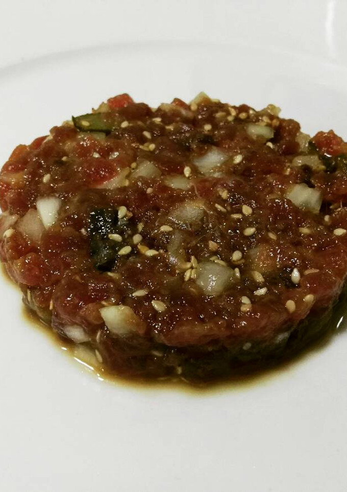 Una foto de Tartár de atún con semillas de sésamo y pepinillos