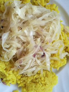 A picture of Fried cabbage with yellow rice.