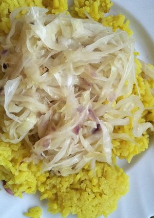 A picture of Fried cabbage with yellow rice.