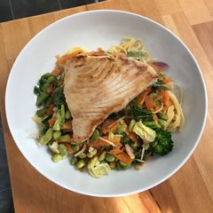 A picture of Tuna steak with egg noodles and stir fry veg.