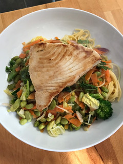 A picture of Tuna steak with egg noodles and stir fry veg.