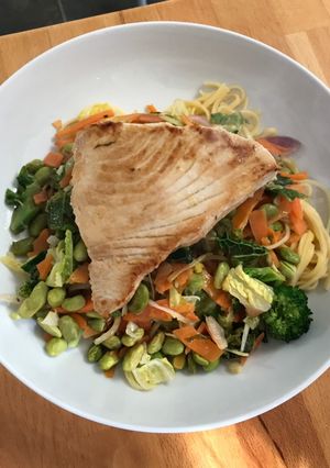 A picture of Tuna steak with egg noodles and stir fry veg.