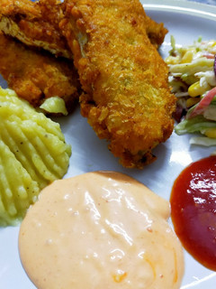 A picture of Fried fish restaurant style with salad,mash potato and dips.