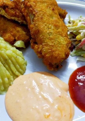 A picture of Fried fish restaurant style with salad,mash potato and dips.