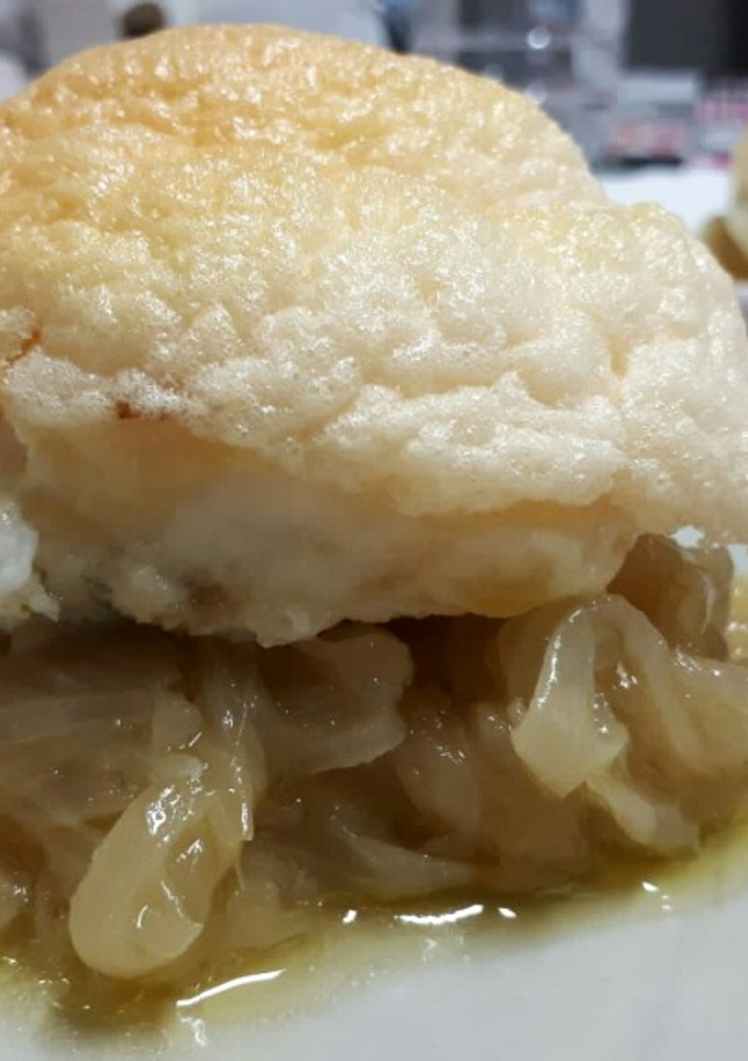 Una foto de Bacalao cubierto de muselina de ajo sobre cebolla caramelizada