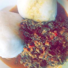 A picture of Tuwon shinkafa with egusi and shredded spinach.
