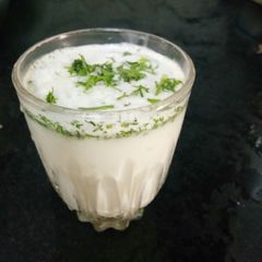 A picture of Masala lassi with coriander leaves.