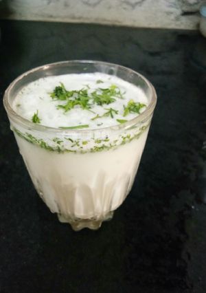 A picture of Masala lassi with coriander leaves.