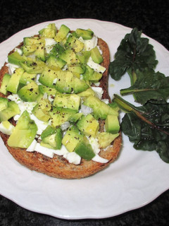 Una foto de Rebanas de pan rústico integral tostado con queso fresco tradicional y aguacate