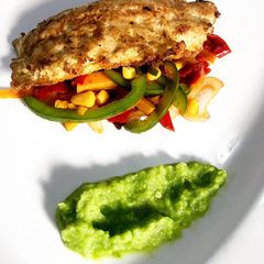 A picture of Deep fried fish fillet on a bed of sautéed vegetables & pea purée.