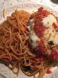 Milanesa de pollo parmesano sobre pasta pomodoro