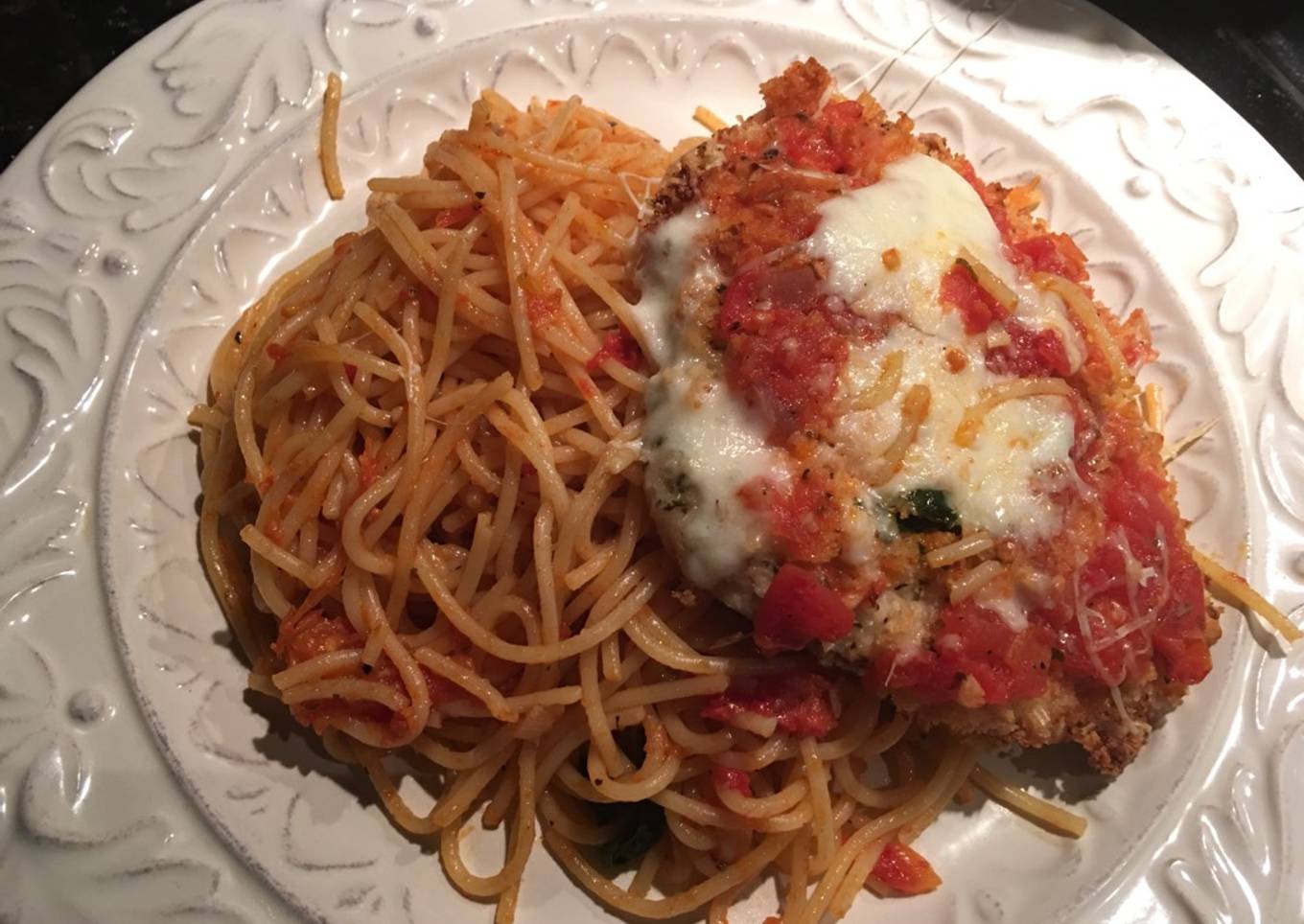 Milanesa de pollo parmesano sobre pasta pomodoro