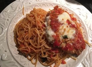 Una foto de Milanesa de pollo parmesano sobre pasta pomodoro