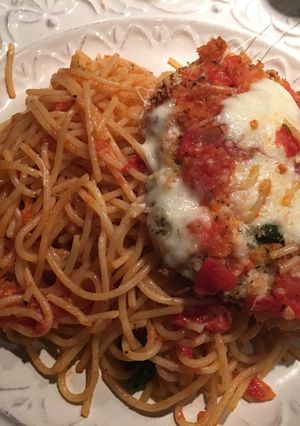 Una foto de Milanesa de pollo parmesano sobre pasta pomodoro