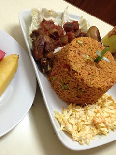 A picture of Jollof rice with salad, pepper kpomo and fried chicken.