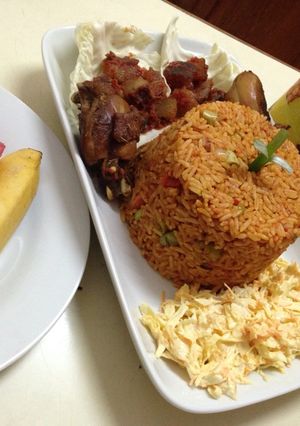 A picture of Jollof rice with salad, pepper kpomo and fried chicken.