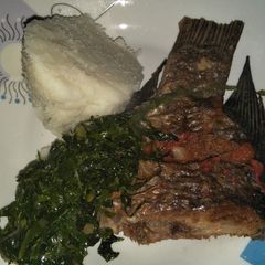A picture of Fried fish with greens and ugali.