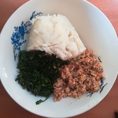 A picture of Scrambled eggs with ugali and kales.