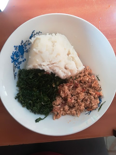 A picture of Scrambled eggs with ugali and kales.