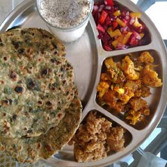 A picture of Methi paranthe with chaas aalu Gobhi sabji, salad and halwa.